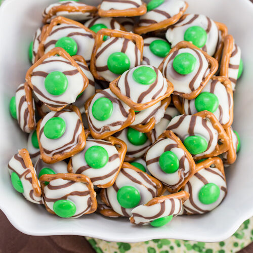 Pretzels with white chocolate and green candies pressed on top.