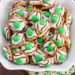 Pretzels with white chocolate and green candies pressed on top.