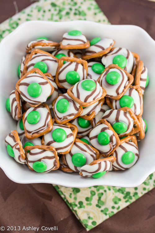 Pretzels with white chocolate and green candies pressed on top.