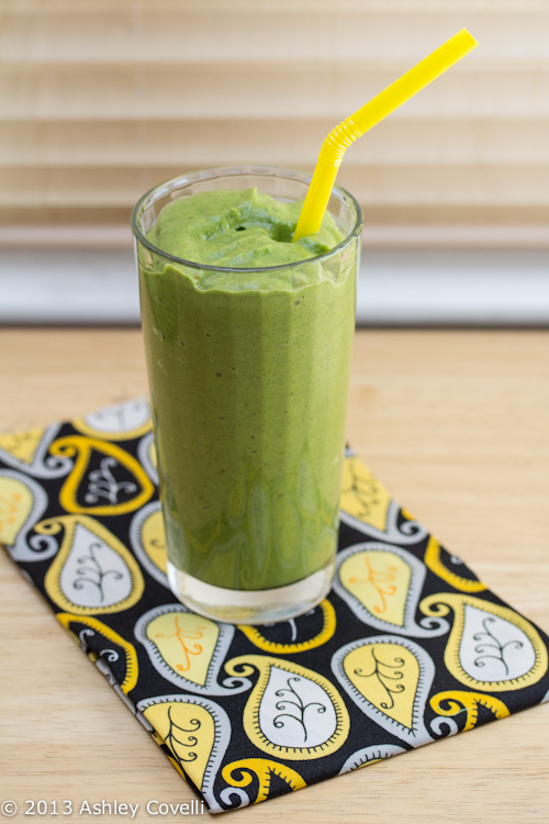 Green smoothie in a glass with a yellow straw.