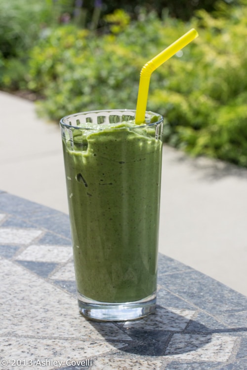 Green smoothie in a glass on a table outside.