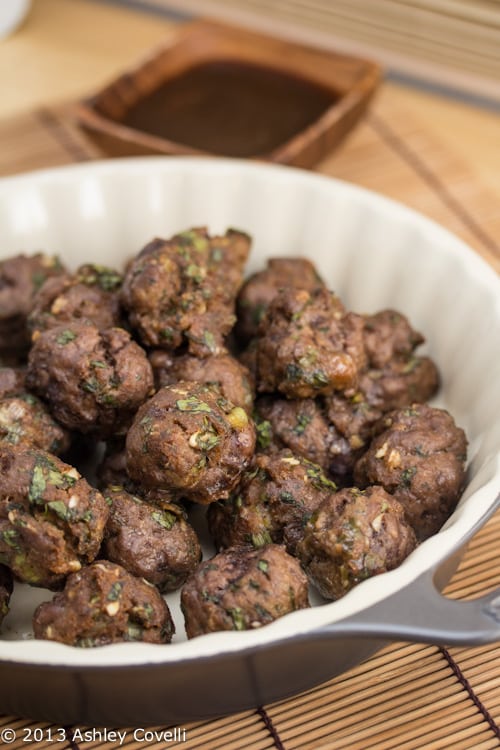 Meatballs in a dish with a dipping sauce alongside.