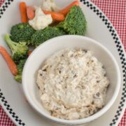 Caramelized onion dip in a bowl with fresh veggies alongside.