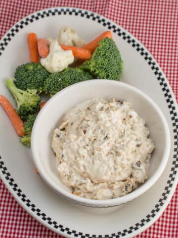 Caramelized onion dip in a bowl with fresh veggies alongside.