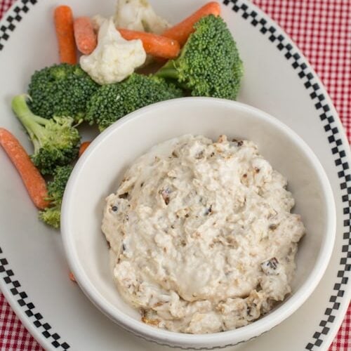 Caramelized onion dip in a bowl with fresh veggies alongside.