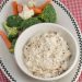 Caramelized onion dip in a bowl with fresh veggies alongside.
