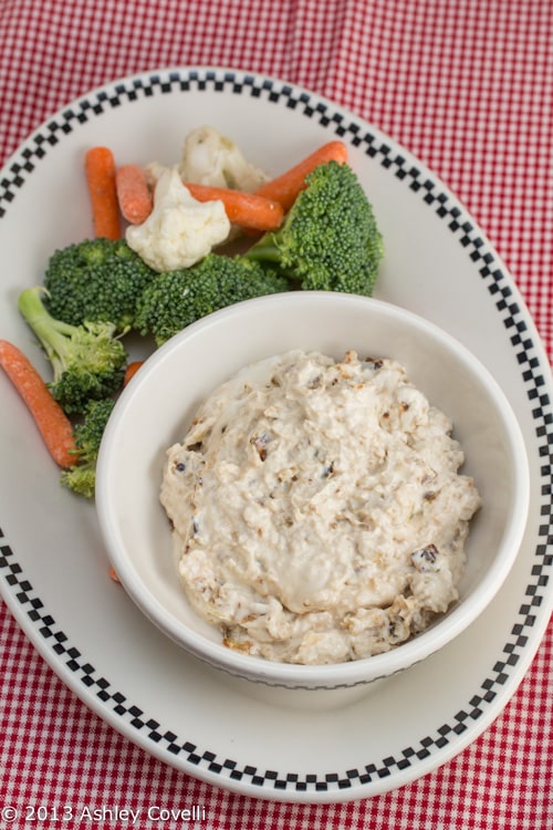 Caramelized onion dip in a bowl with fresh veggies alongside.