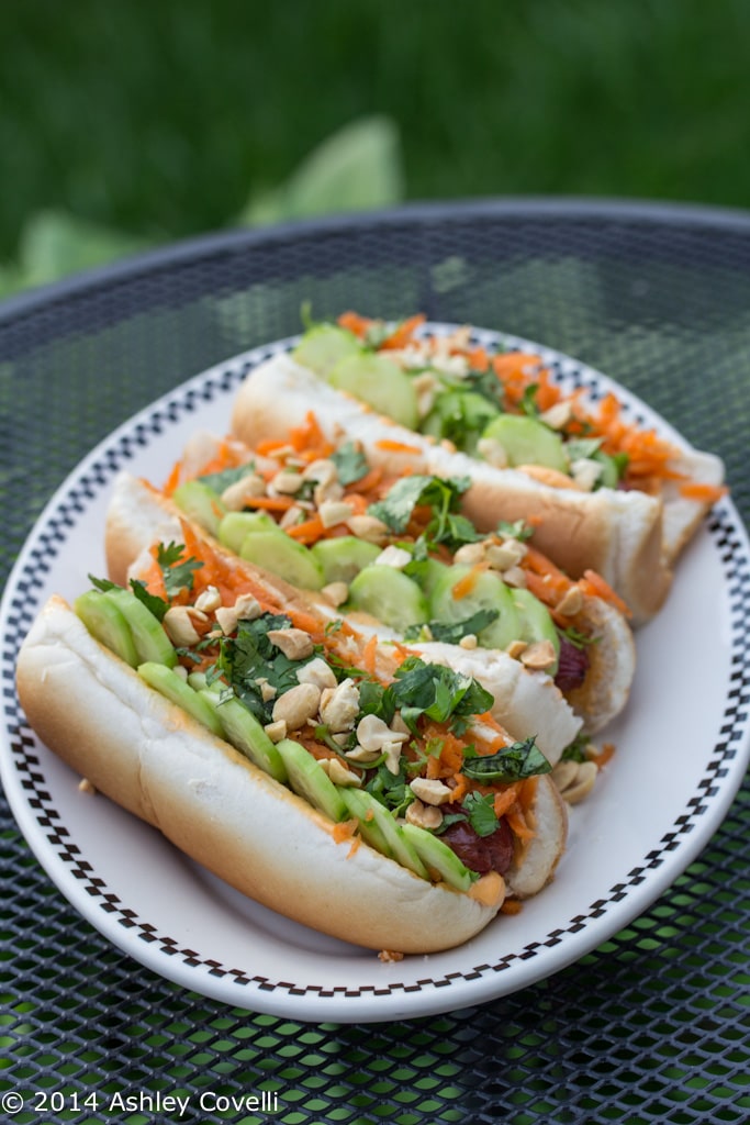 Hot dogs on a plate with various banh mi toppings.