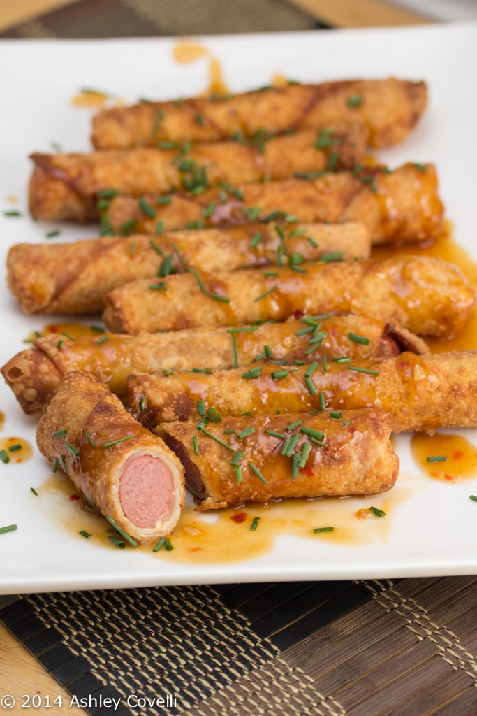 Platter of fried hot dogs sprinkled with chives, with one cut in half.