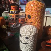 Halloween candy displayed in glass jars with faces on them.