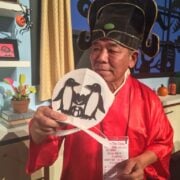 Man showing off hand-cut penguin paper art.