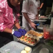 Chef plating macarons shaped like burgers.
