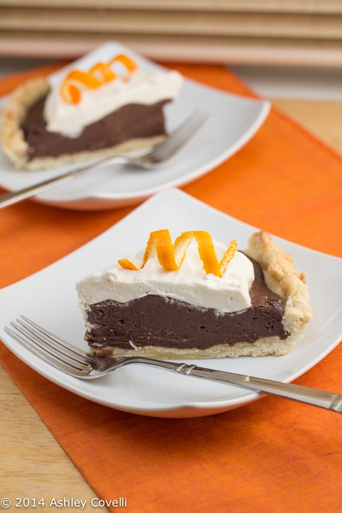 Plates with slices of chocolate cream pie with orange zested whipped cream.