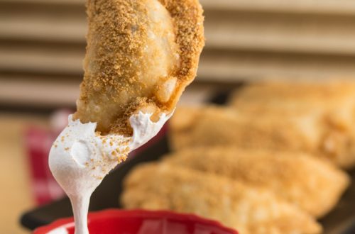 Dunking a Deep Fried Nutella S’mores Dumpling into marshmallow fluff.