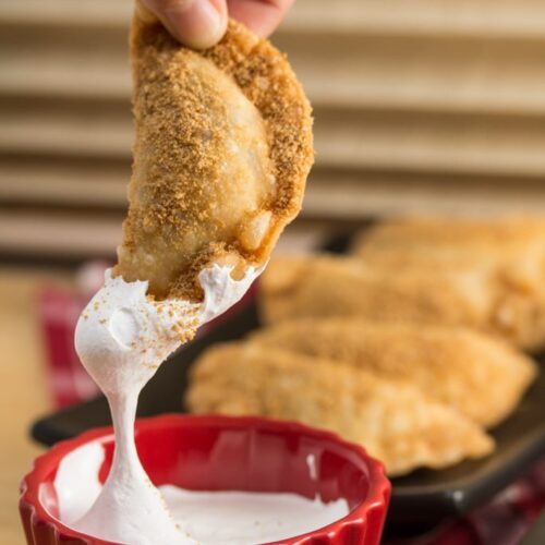 Dunking a Deep Fried Nutella S’mores Dumpling into marshmallow fluff.