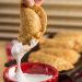 Dunking a Deep Fried Nutella S’mores Dumpling into marshmallow fluff.