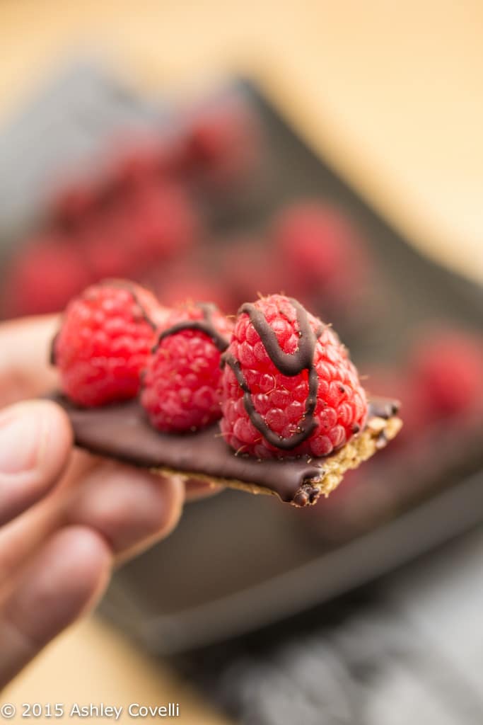 Hand holding chocolate covered raspberry petit fours.