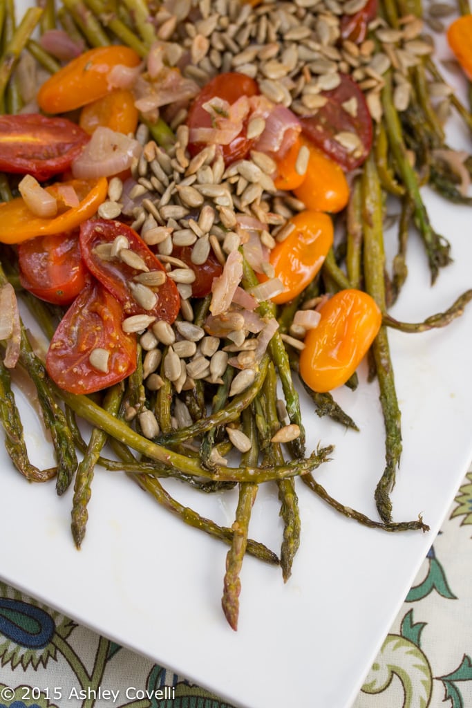 Roasted asparagus and tomatoes topped with toasted sunflower seeds.