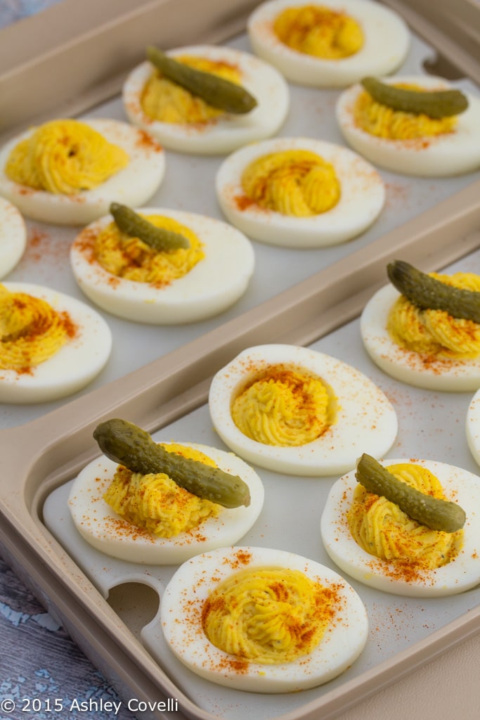 Platter of deviled eggs garnished with cornichons.