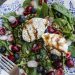 Overhead view of a plate of salad topped with fruit, vegetables, and burrata cheese drizzled with aged balsamic.