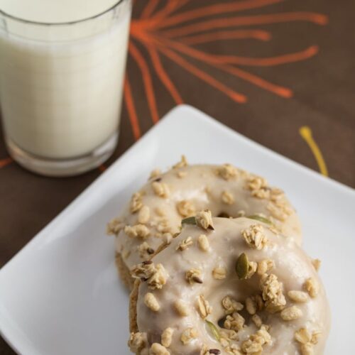 Baked Apple Spice Donuts with Maple Frosting and Pumpkin Granola (#ad): Crunchy granola is a perfect topping for these apple + Greek yogurt infused baked donuts. A great breakfast or dessert recipe to use your fall apple bounty! #StonyfieldBlogger
