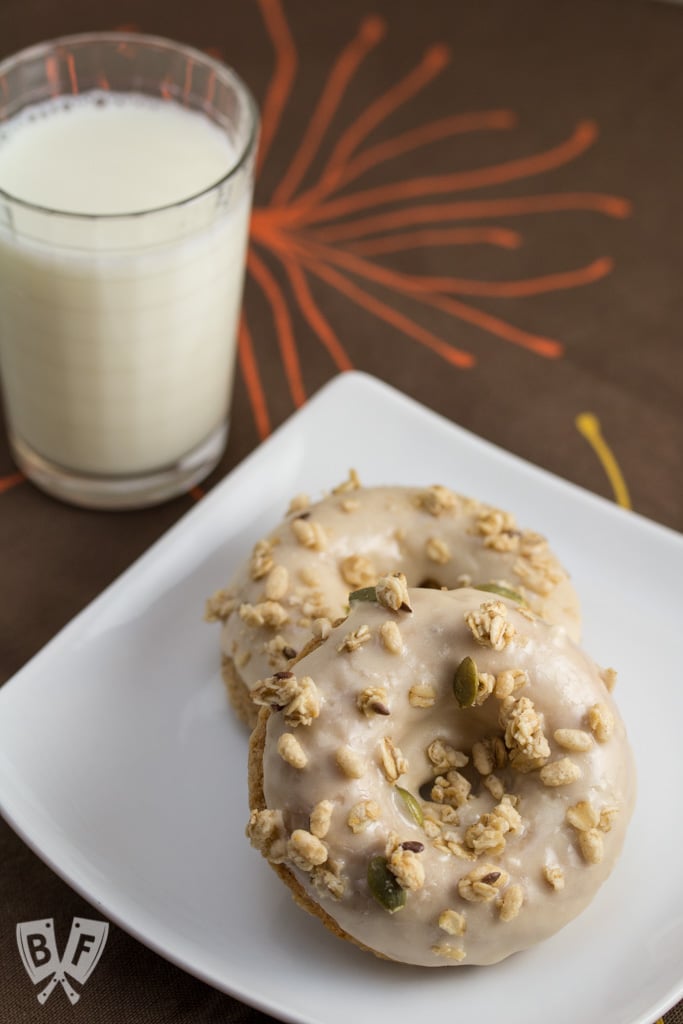 Baked Apple Spice Donuts with Maple Frosting and Pumpkin Granola (#ad): Crunchy granola is a perfect topping for these apple + Greek yogurt infused baked donuts. A great breakfast or dessert recipe to use your fall apple bounty! #StonyfieldBlogger