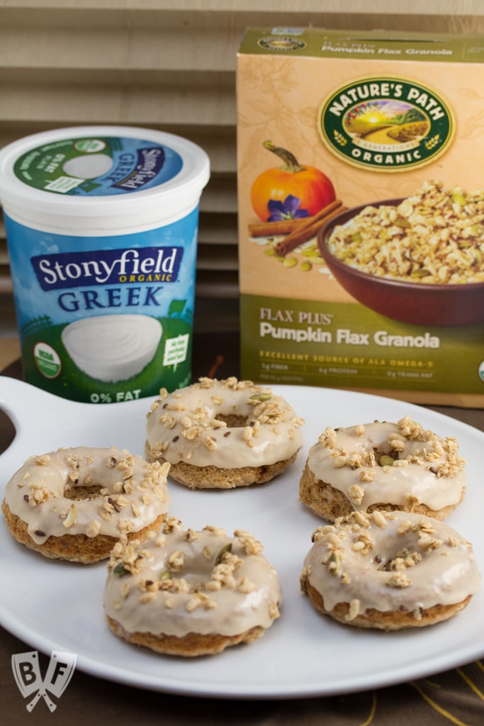 Baked Apple Spice Donuts with Maple Frosting and Pumpkin Granola (#ad): Crunchy granola is a perfect topping for these apple + Greek yogurt infused baked donuts. A great breakfast or dessert recipe to use your fall apple bounty! #StonyfieldBlogger