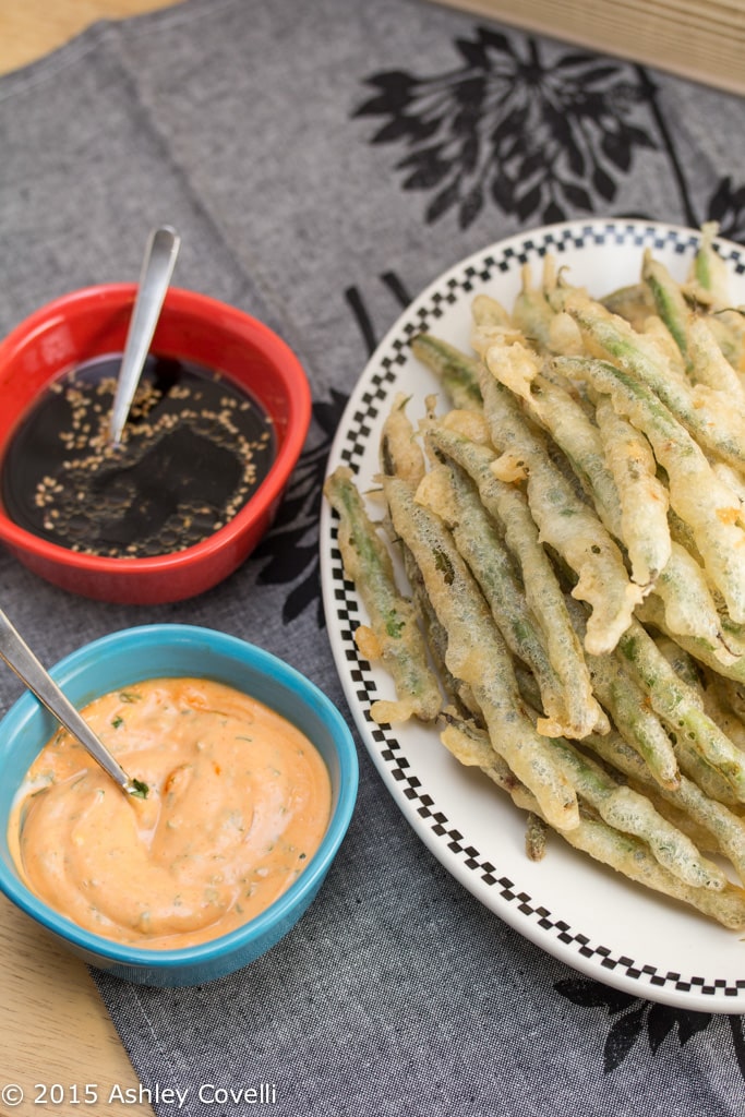 Overhead view of Tempura Green Beans with Sriracha Aioli + Soy Ginger Dipping Sauces.