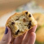 Hand holding a banana chocolate chip muffin with a bite taken out of it.