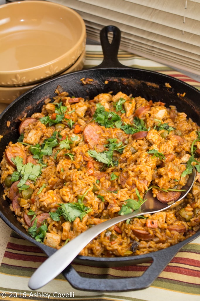 Overhead view of a cast iron skillet full of Spanish chicken, sausage, and rice.