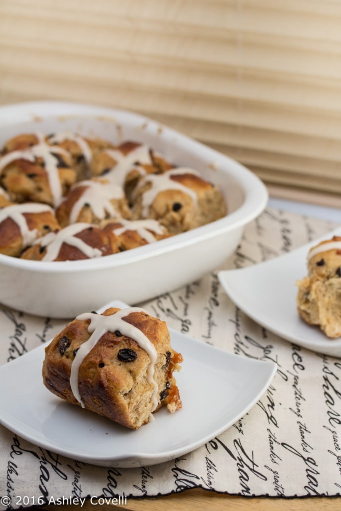 Tray of hot cross buns with 2 served on plates.