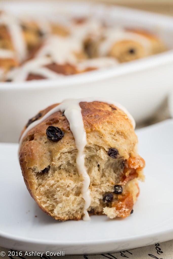 Close up of a hot cross bun with dripping icing.