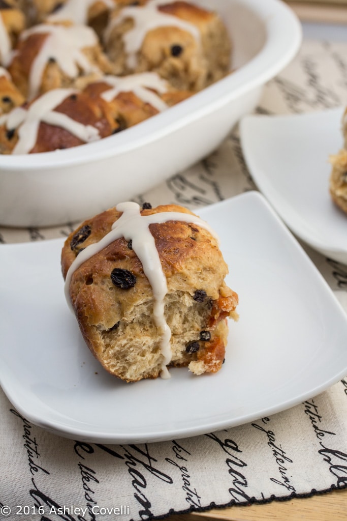 Close up of a hot cross bun on a plate.