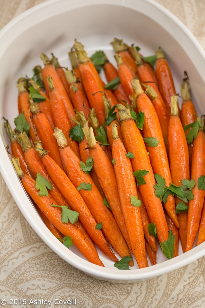 Roasted carrots in a dish topped with fresh parsley.