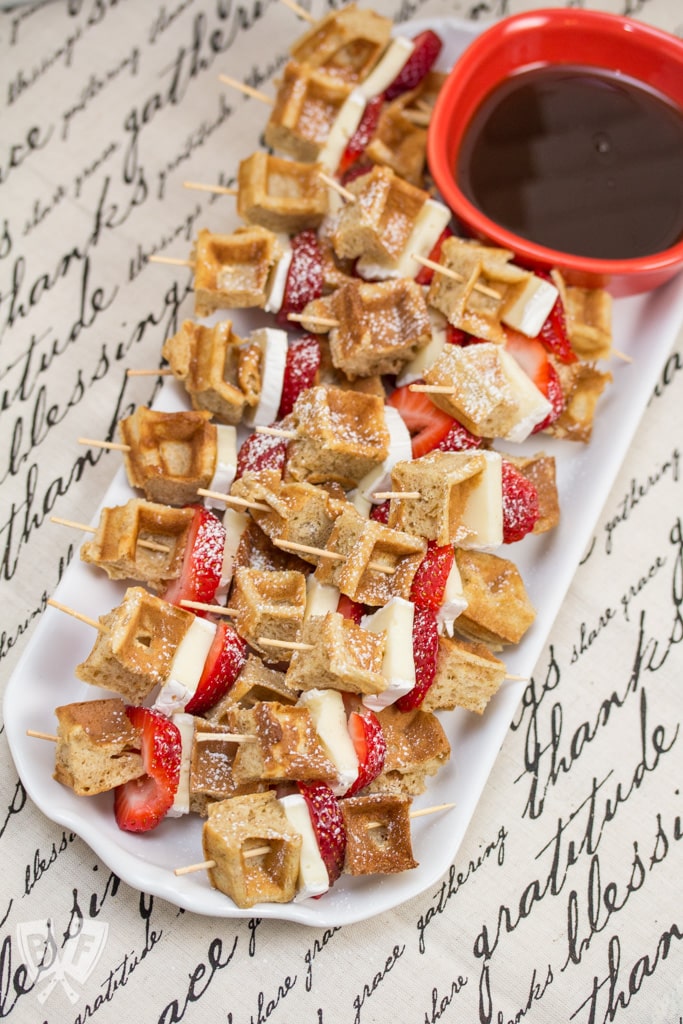 Brie and waffle skewers with strawberries and maple syrup.