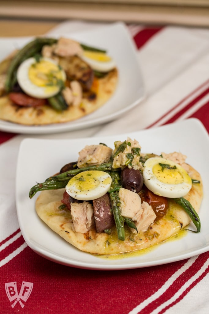 Mini naan breads topped with grilled Niçoise salad ingredients.