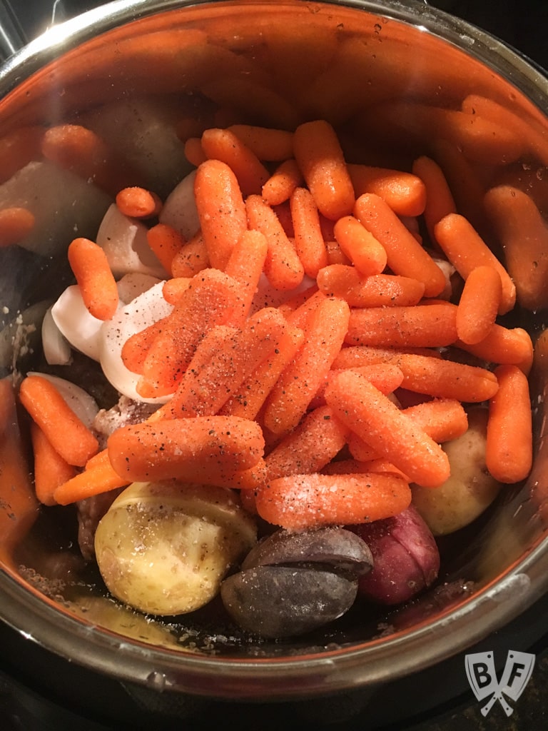 Instant Pot filled with potatoes, onions, and baby carrots.