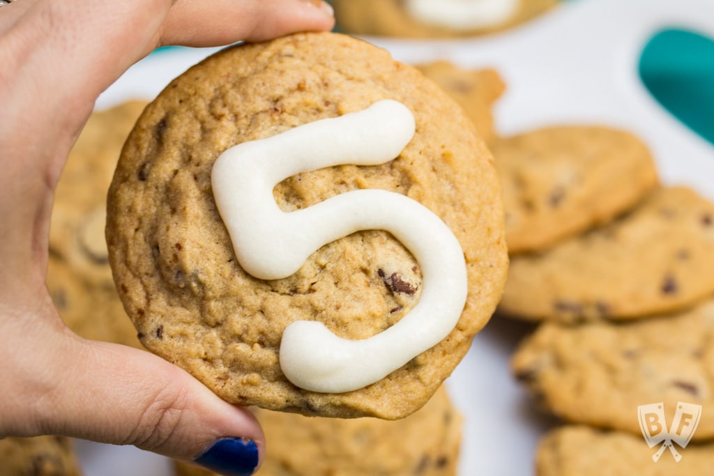 Close up of a chocolate chip cookie with the number 5 written in icing.
