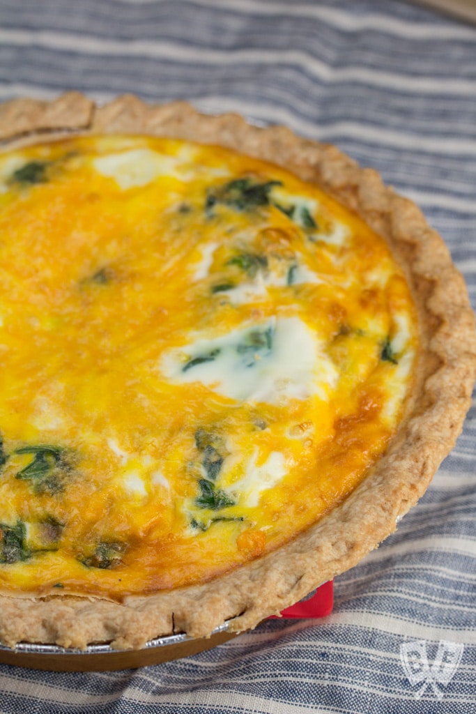 Overhead view of a full baby spinach and cheddar quiche