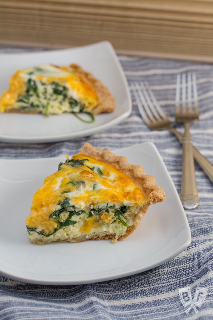 2 plates with slices of baby spinach and cheddar quiche