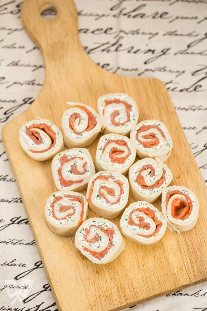 Overhead view of smoked salmon roll-ups on a cutting board.