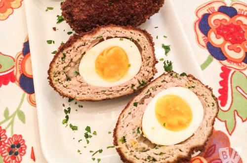 An overhead view of a Turkey-Scotch Egg, cut in half to reveal the turkey sausage and soft-boiled egg inside.