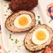 An overhead view of a Turkey-Scotch Egg, cut in half to reveal the turkey sausage and soft-boiled egg inside.