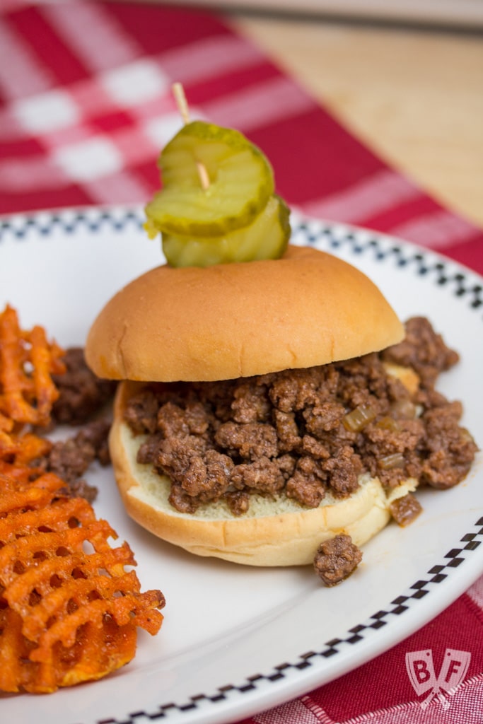 A sloppy joe sandwich on a plate with sweet potato fries