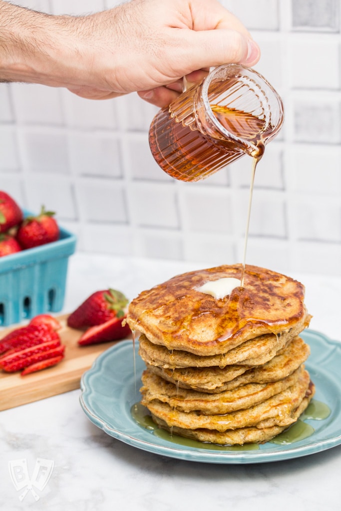 Pouring syrup onto a stack of buttermilk pancakes