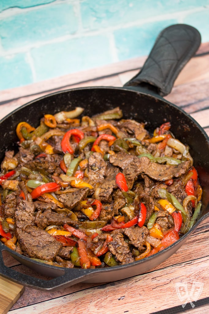 Overhead view of an iron skillet filled with steak fajitas.