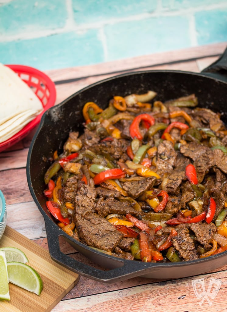 Cast iron skillet filled with steak fajita mixture.