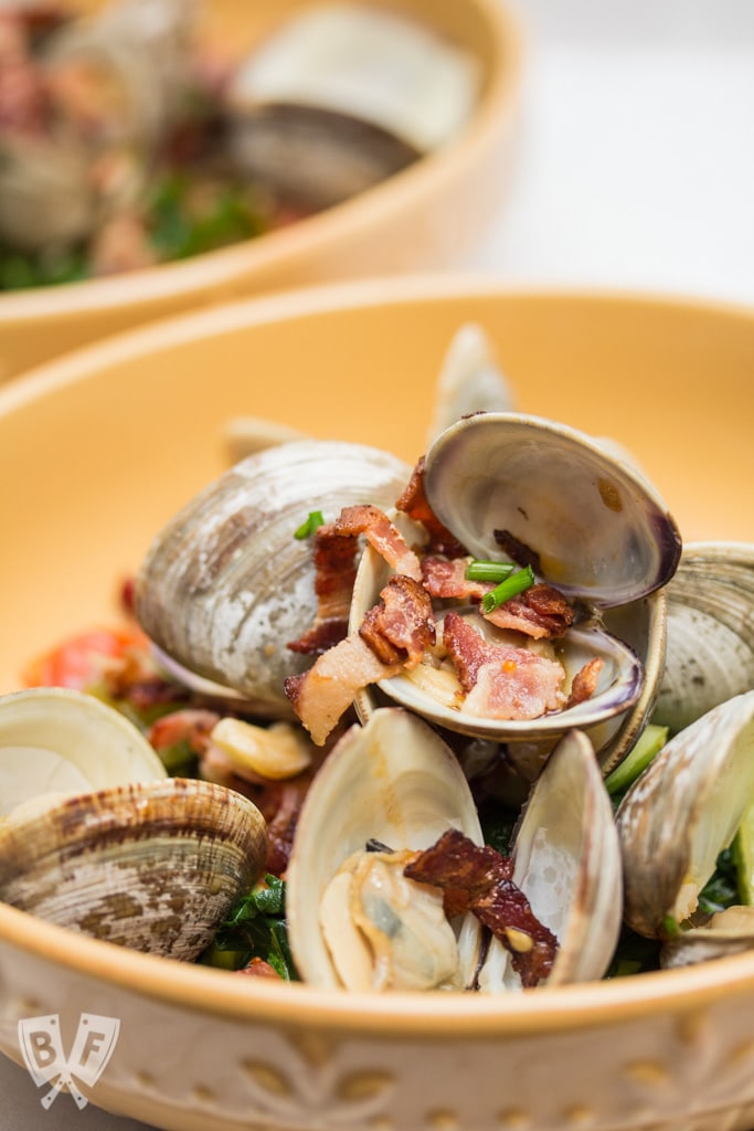 Garlicky Littleneck Clams with Bacon + Wine Over Sautéed Spring Veggies: A bed of sautéed veggies makes the perfect base for this bacon-loaded seafood dish. Make sure you have plenty of crusty bread for dunking! #BaconMonth