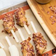 Banana halves on popsicle sticks coated in peanut butter and bacon.