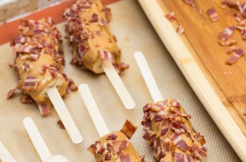 Banana halves on popsicle sticks coated in peanut butter and bacon.